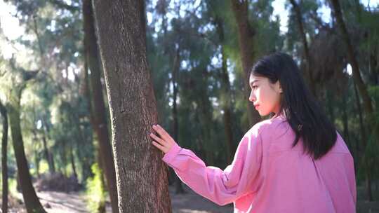 阳光下美女手抚摸树亲近自然感受大自然美好