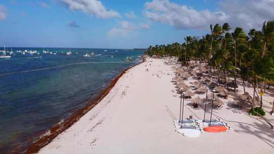 满是日光浴床的沙滩，加勒比海上的船只，多米尼加共和国蓬塔卡纳的巴瓦罗度假村，