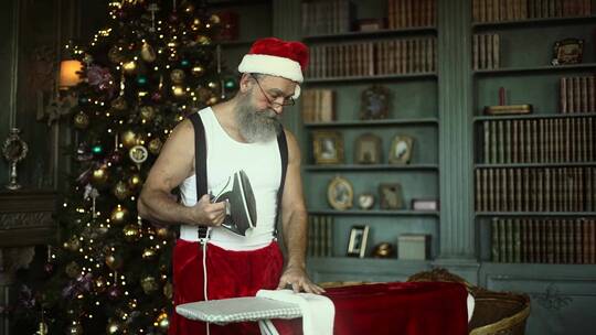 穿着圣诞老人服装的男人在熨烫衣服
