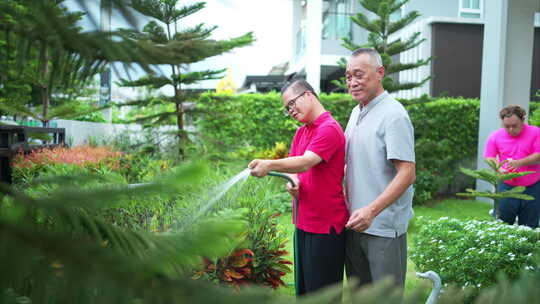 在他们的休息日祖父和孙子帮助浇水的树木在