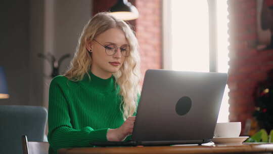 女性Smm专家远程工作，坐在咖啡馆的桌子旁，使用带免费Wifi的笔记本电脑