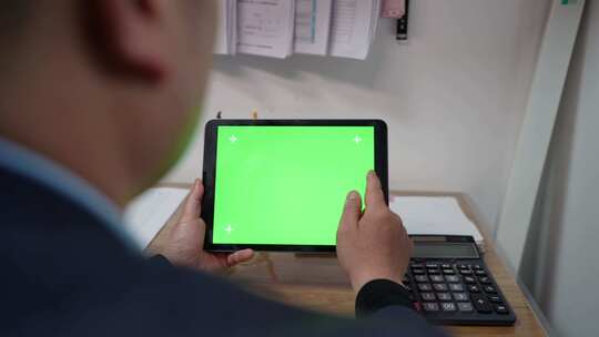 男子低头触屏绿色屏幕的iPad视频素材模板下载