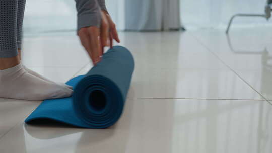 特写腿女人在地板上滚动体操垫瑜伽训练认不