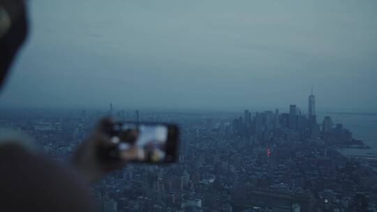 女人站在高处用手机拍摄城市景观