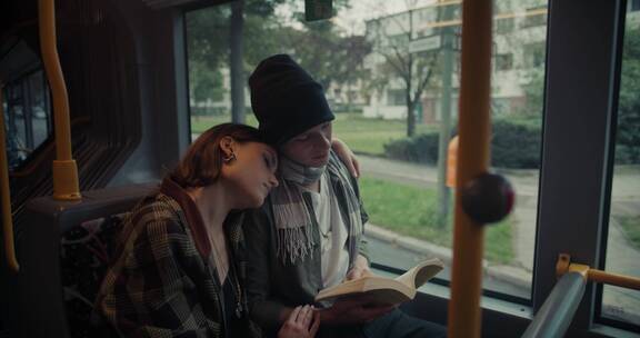 情侣坐在公交车上看书