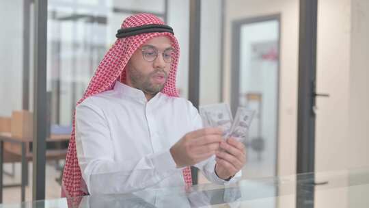 年轻的阿拉伯人在工作中数钱视频素材模板下载