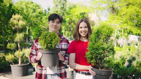 可爱的已婚多种族夫妇拿着美丽的盆栽植物开