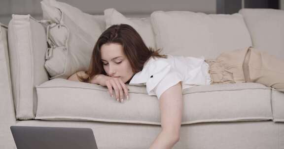 女孩躺在沙发上在电脑上打字