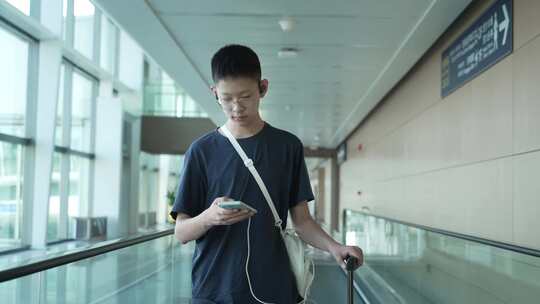 男孩子暑假出行在机场用手机