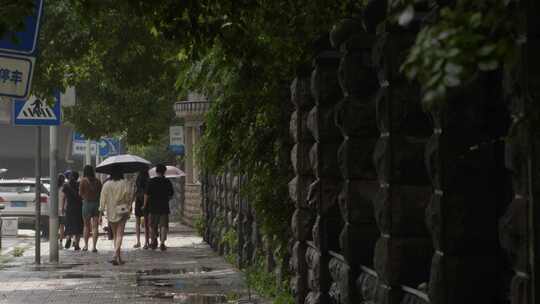 城市雨中围墙街边行人背影