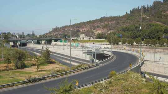 圣地亚哥，白天，靠近Bicentenario公园和林地山坡的Costanera Sur大道的交通