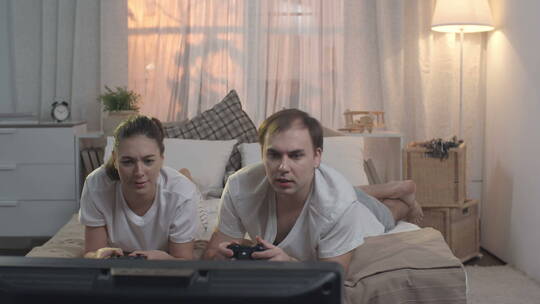 情侣趴在床上玩电子游戏