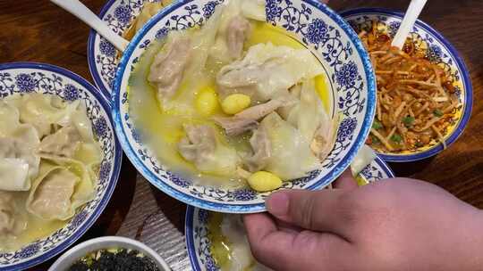 手端青花瓷碗内装馄饨等特色食物