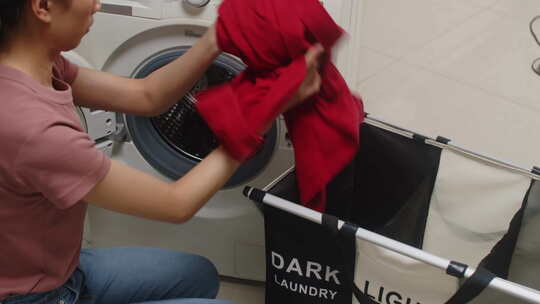 女孩分拣深色和浅色洗衣和装载洗衣机
