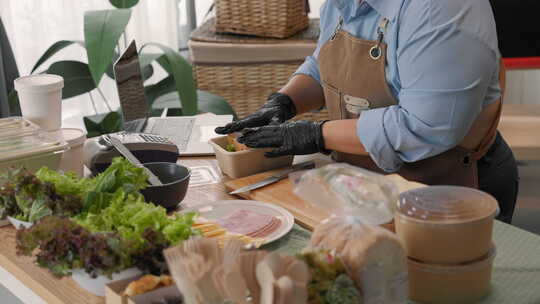 亚洲女性在家庭云厨房为在线食品订单准备健