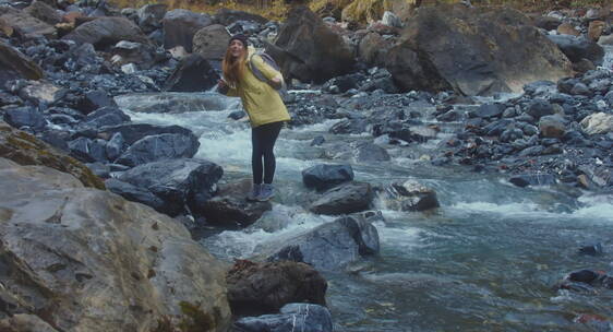 女孩站在河边的岩石上跳舞