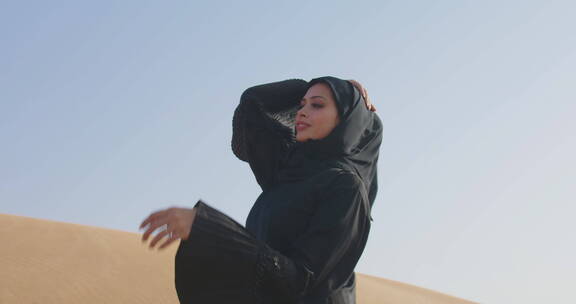 穆斯林女人在多风的沙漠中摆姿势