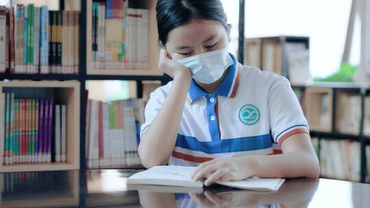 戴口罩的初中生坐在学习图书馆看书学习4k
