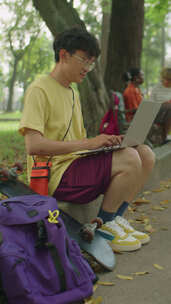 亚洲学生在公园笔记本电脑上使用互联网