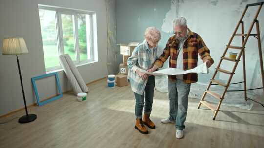 老人和女人正在浏览带有公寓平面图的床单并讨论装修