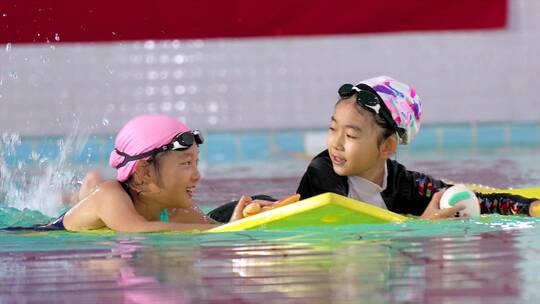 两个在泳池中玩耍玩水的中国女孩