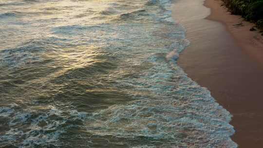日落时沙滩上的波浪，棕榈树