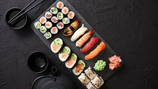 各种不同种类的寿司卷放在黑色石板上