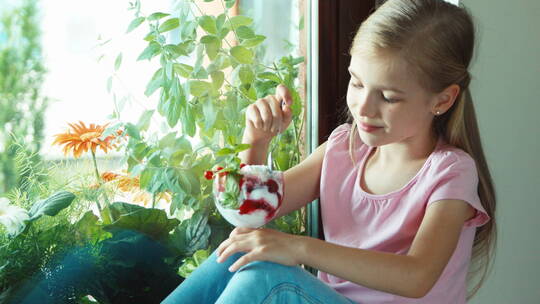 女孩坐在窗台上吃冰淇淋并微笑点头