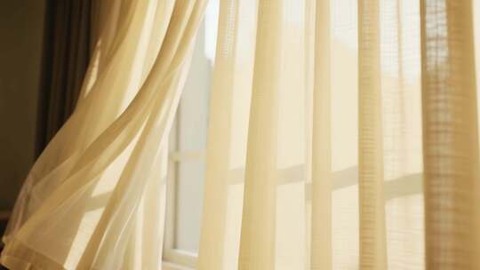 窗边轻柔飘动的米黄色窗帘