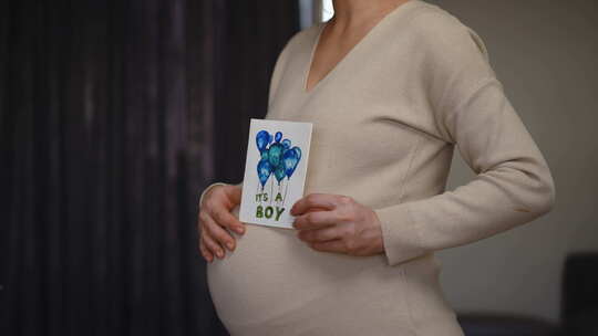 一名无法辨认的孕妇用一只手拿着生日贺卡的