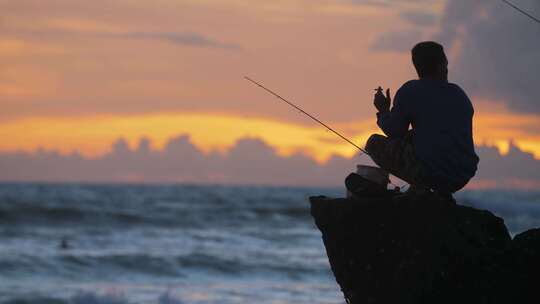 海边夕阳下钓鱼的人剪影