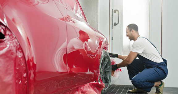 男性汽车油漆工小心地在服务中的汽车上涂抹