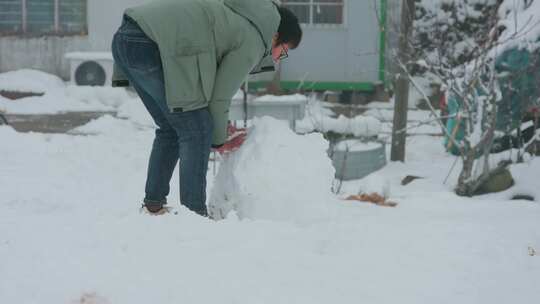 男子户外院子堆雪人滚雪球场景