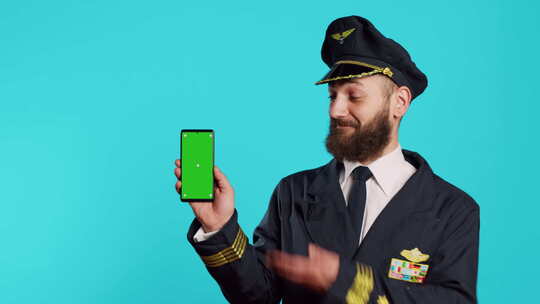 微笑的男飞行员使用带绿屏的电话
