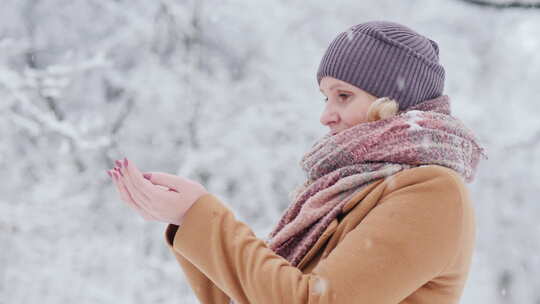 迷人的女人手掌抓雪花享受美丽的冬日