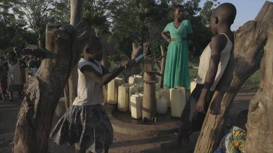 非洲女孩按压旧式井打水