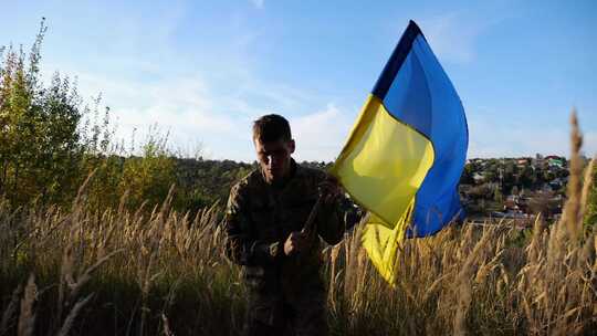 穿着制服的年轻男性军人挥舞着乌克兰国旗走
