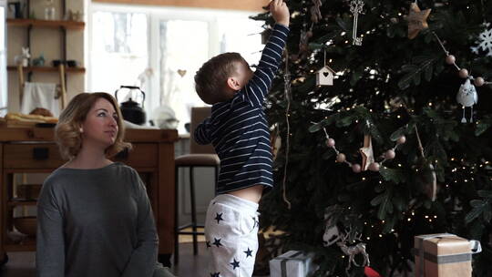 在圣诞树上放装饰物的男孩视频素材模板下载
