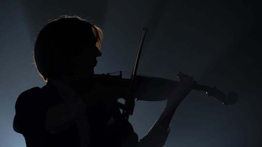 小提琴手在黑暗的工作室里用灯笼表演