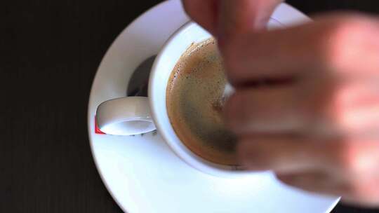 俯拍往咖啡杯里放入白糖并搅拌均匀
