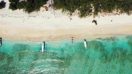 热带岛屿，有白色沙滩和停泊的旅游船，空中视频素材模板下载