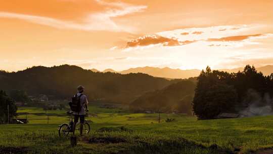 清晨朝阳下男子在乡下田间小路上骑行自行车
