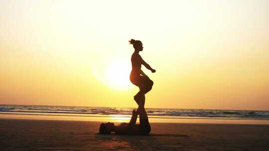 适合运动情侣一起在沙滩上练习Acro瑜伽