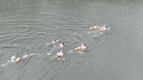 雨中多人在户外水域游泳的俯拍画面