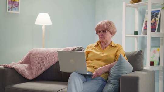 疲惫的戴眼镜的老年妇女坐在沙发上治疗近视