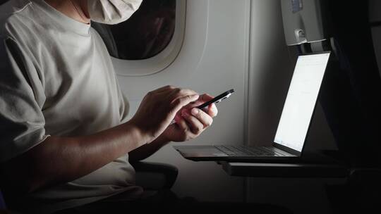 疫情期间男子在飞机上使用手机和笔记本电脑