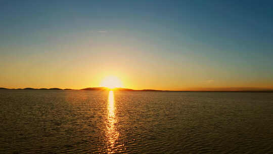 航拍湖边的落日、夕阳下的蓝色湖水、青海湖