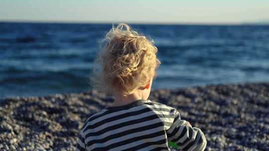 男孩坐在海滩上玩耍