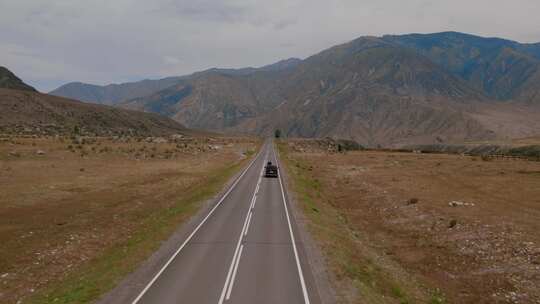 阿尔泰山脉山谷，在戏剧性的天空下，楚亚高速公路上有交通车辆