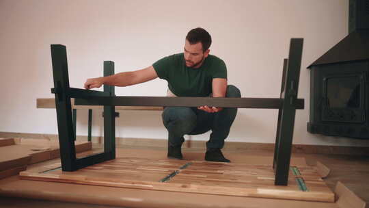 男人组装桌子，把螺丝放在金属腿上——宽镜头视频素材模板下载